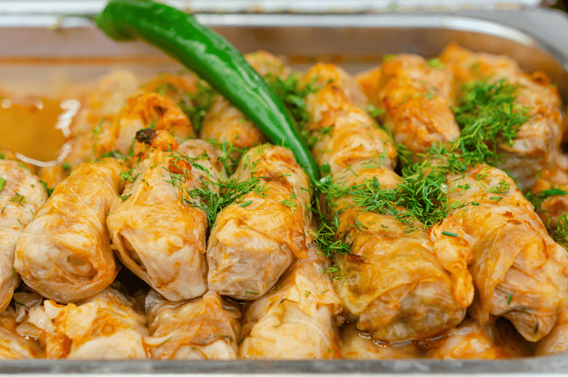 Cooked Sarmale in a metal serving tray, heavily garnished with fresh chopped dill and topped with a whole green chili pepper. Cooked Sarmale in a metal serving tray, heavily garnished with fresh chopped dill and topped with a whole green chili pepper.