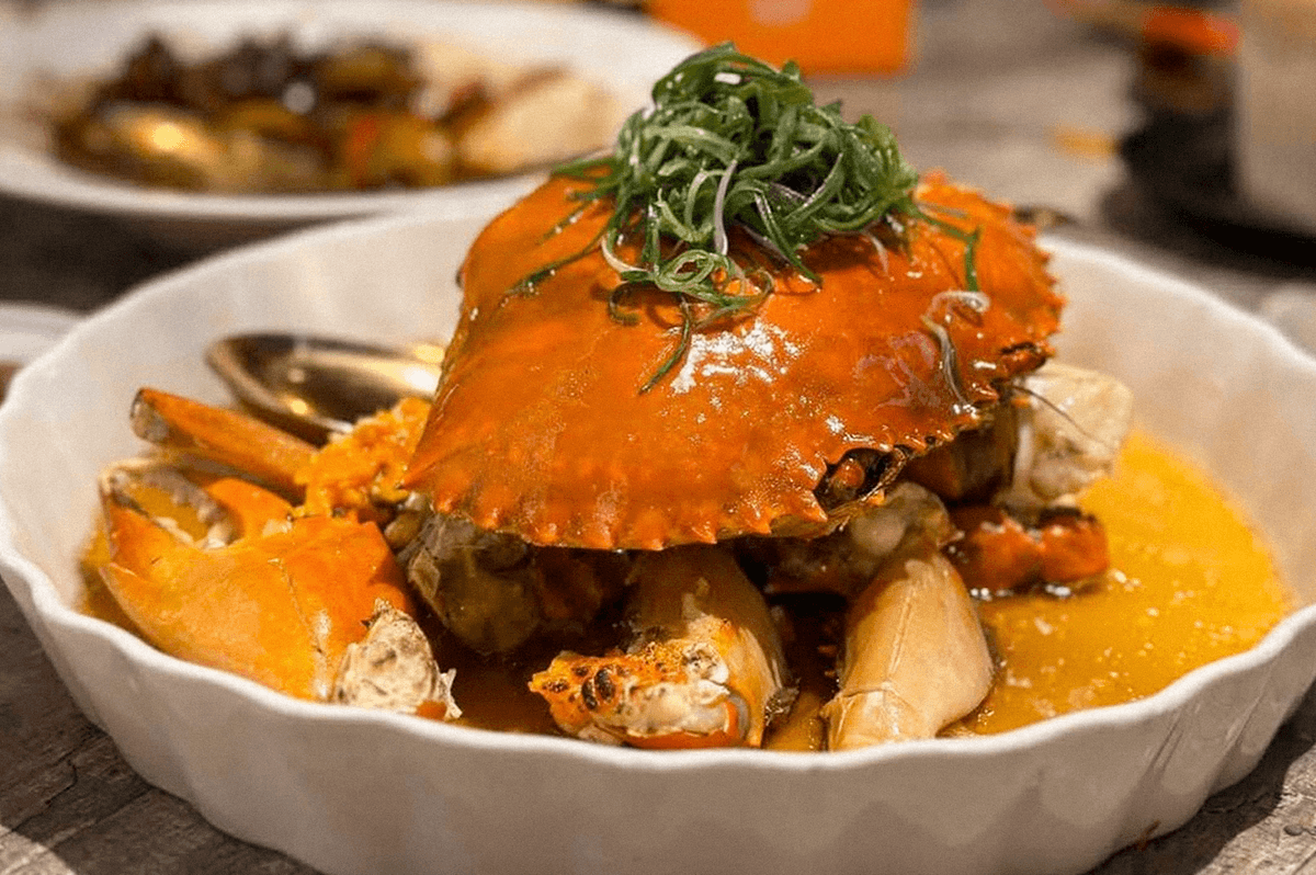 A whole crab served with shrimp and other seafood in a savory sauce, topped with sliced greens. A whole crab served with shrimp and other seafood in a savory sauce, topped with sliced greens.