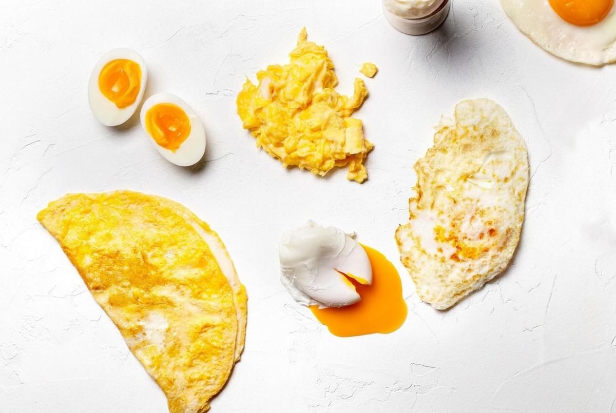 Top-down arrangement of eggs prepared in different ways including scrambled, poached, omelet, and hard-boiled. Top-down arrangement of eggs prepared in different ways including scrambled, poached, omelet, and hard-boiled.