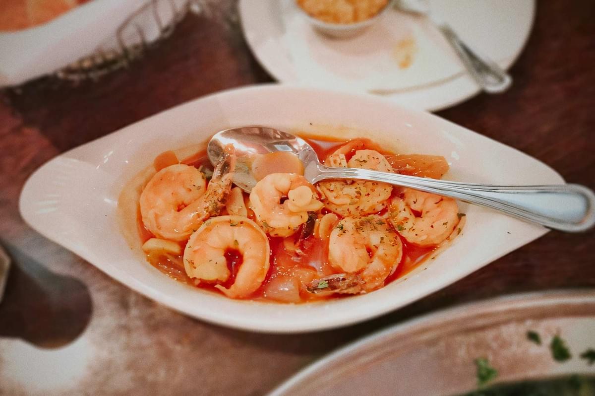 Garlic shrimp (gambas al ajillo ) in spicy tomato sauce garnished with herbs, served in a white oval dish. Garlic shrimp (gambas al ajillo ) in spicy tomato sauce garnished with herbs, served in a white oval dish.