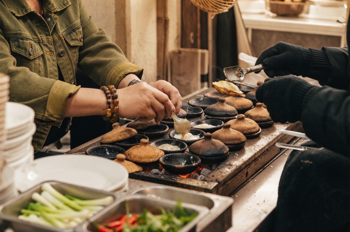 Street food vendor preparing traditional snacks in clay pots at a small business food stall. Street food vendor preparing traditional snacks in clay pots at a small business food stall.