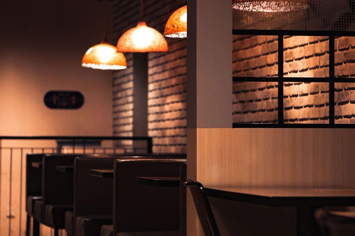Warm lighting inside a cozy restaurant with booths and brick walls, representing a welcoming dining space. Warm lighting inside a cozy restaurant with booths and brick walls, representing a welcoming dining space.