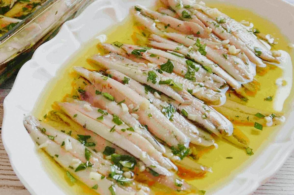 Boquerones en vinagre — fresh anchovy fillets marinated in white wine vinegar, garlic, parsley, and olive oil. Boquerones en vinagre — fresh anchovy fillets marinated in white wine vinegar, garlic, parsley, and olive oil.