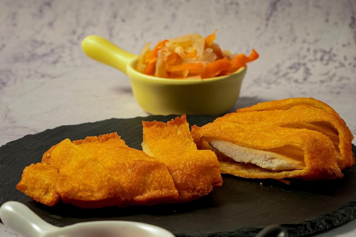 Crispy chicken chop and fried chicken served on a black stone plate with side dishes and sauces. Crispy chicken chop and fried chicken served on a black stone plate with side dishes and sauces.
