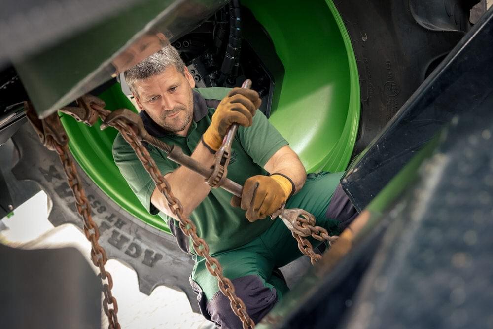 Ein Mann bringt Ketten zur Befestigung unter einem Fahrzeug an Ein Mann bringt Ketten zur Befestigung unter einem Fahrzeug an