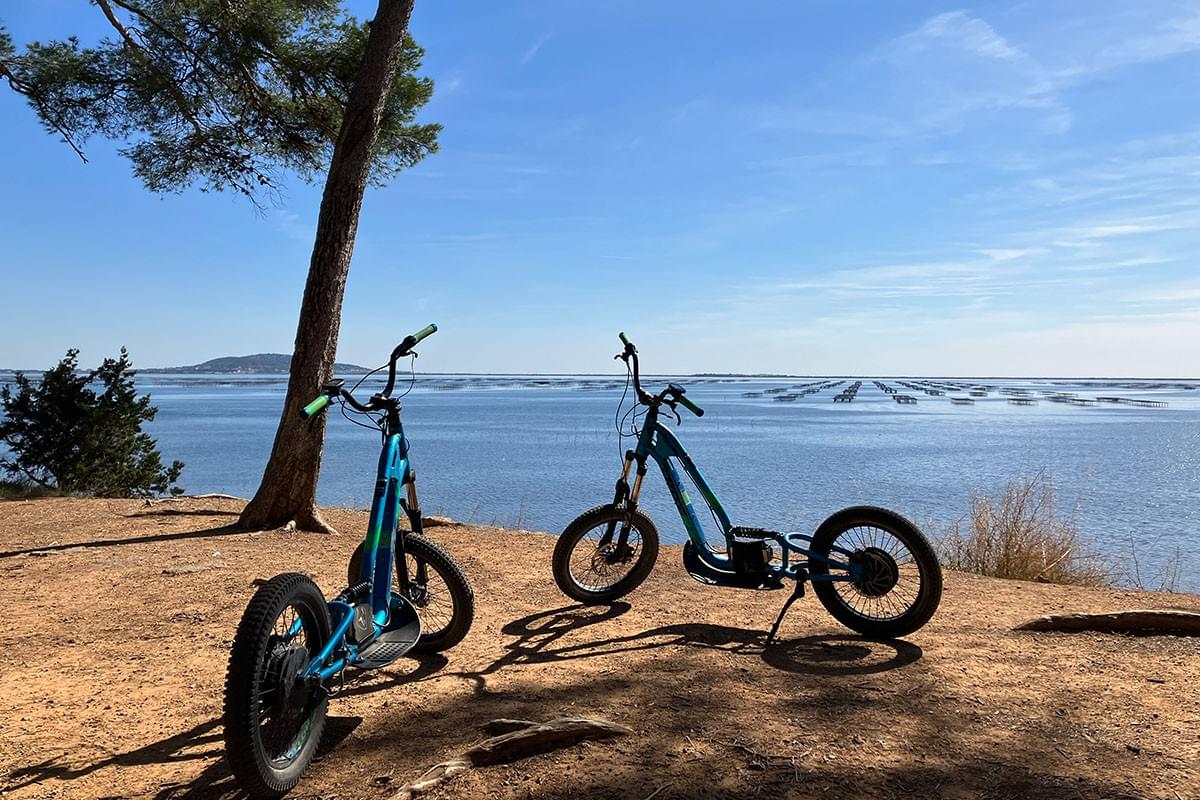 Deux trottinettes électriques tout-terrain devant l'étang de Thau Deux trottinettes électriques tout-terrain devant l'étang de Thau