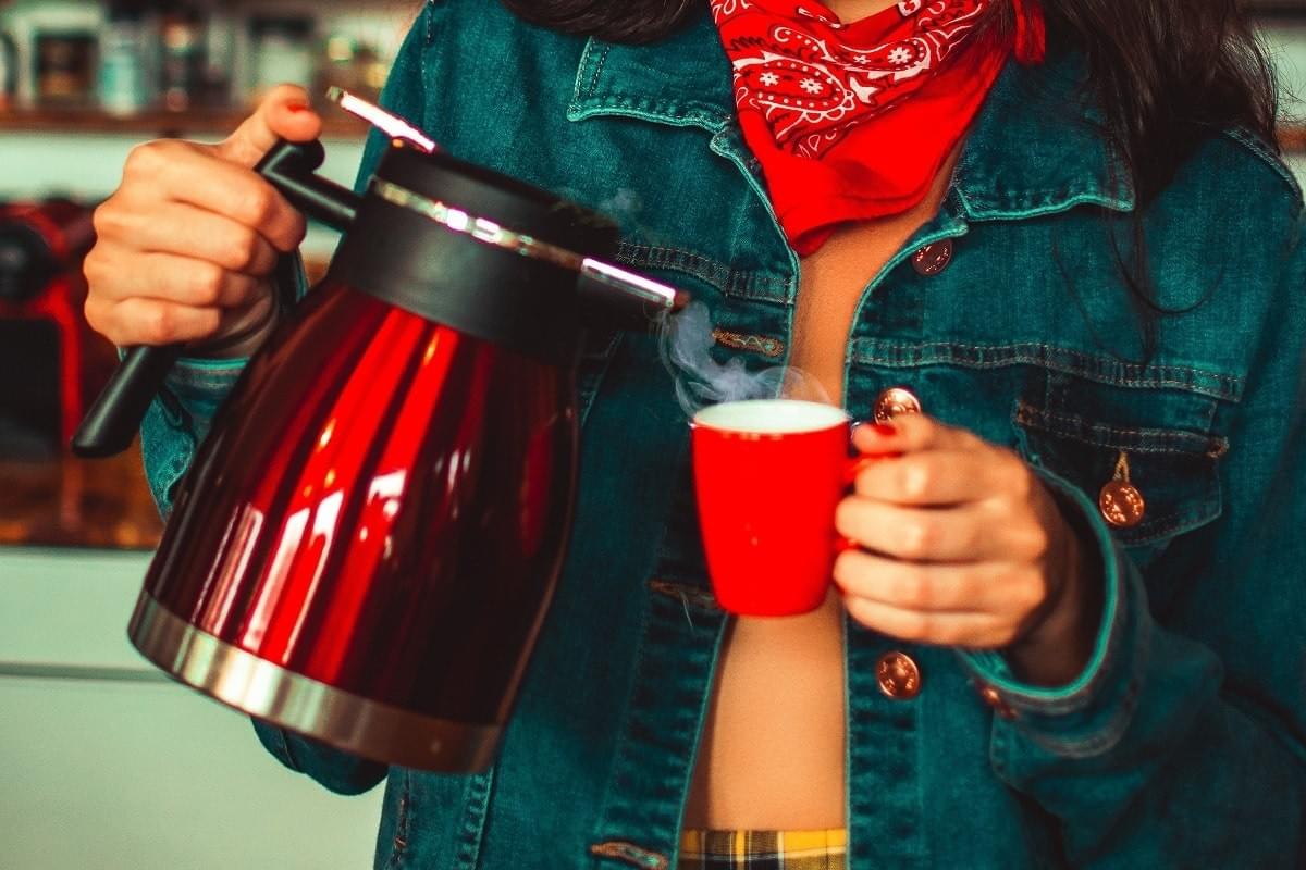 Lady holding a kettle and pouring water into a cup Lady holding a kettle and pouring water into a cup