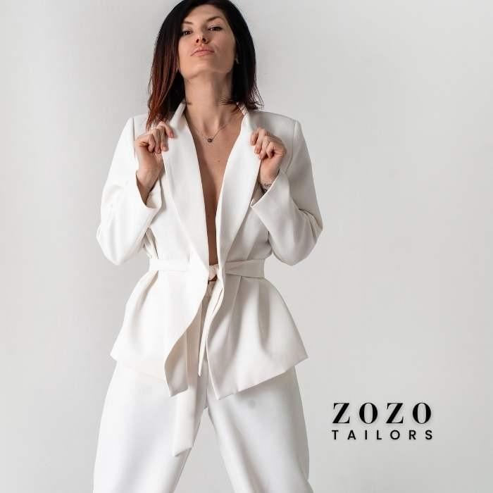 Woman in bespoke white suit stands with confidence — a visual expression of individuality and precision tailoring. Woman in bespoke white suit stands with confidence — a visual expression of individuality and precision tailoring.