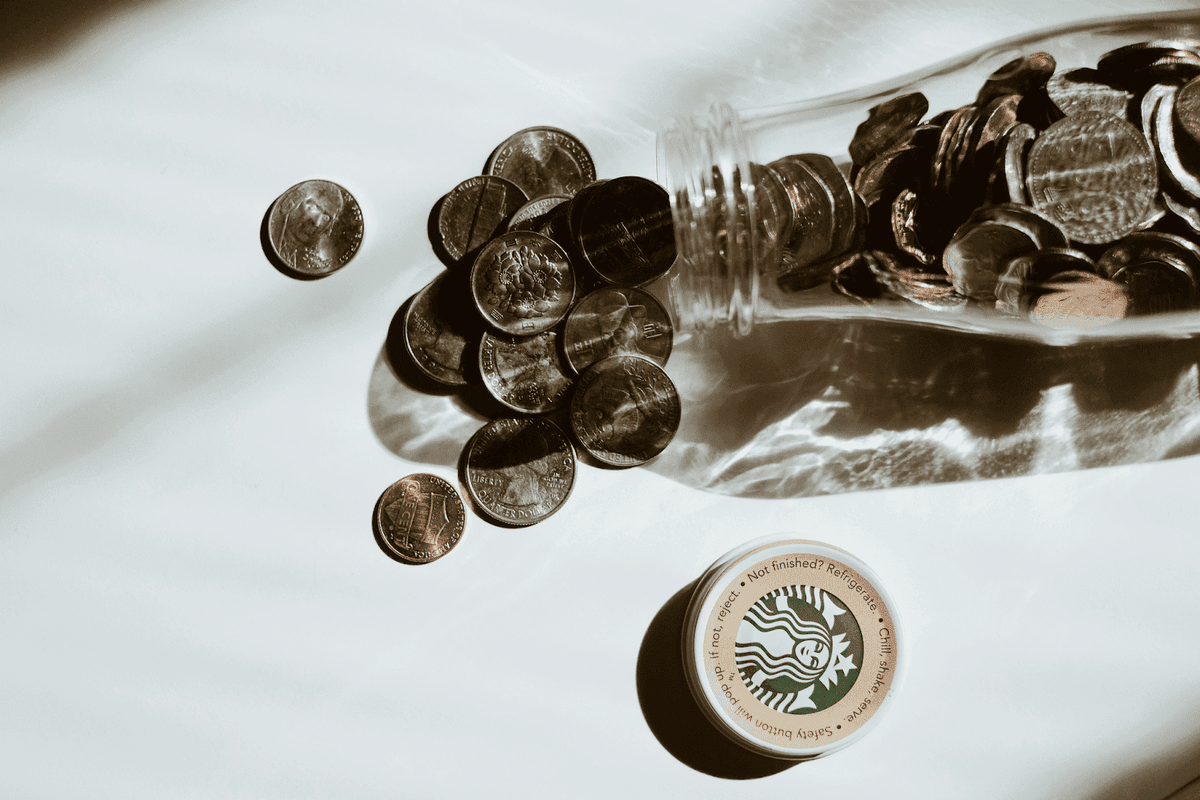 Una persona organizando monedas en diferentes frascos Una persona organizando monedas en diferentes frascos