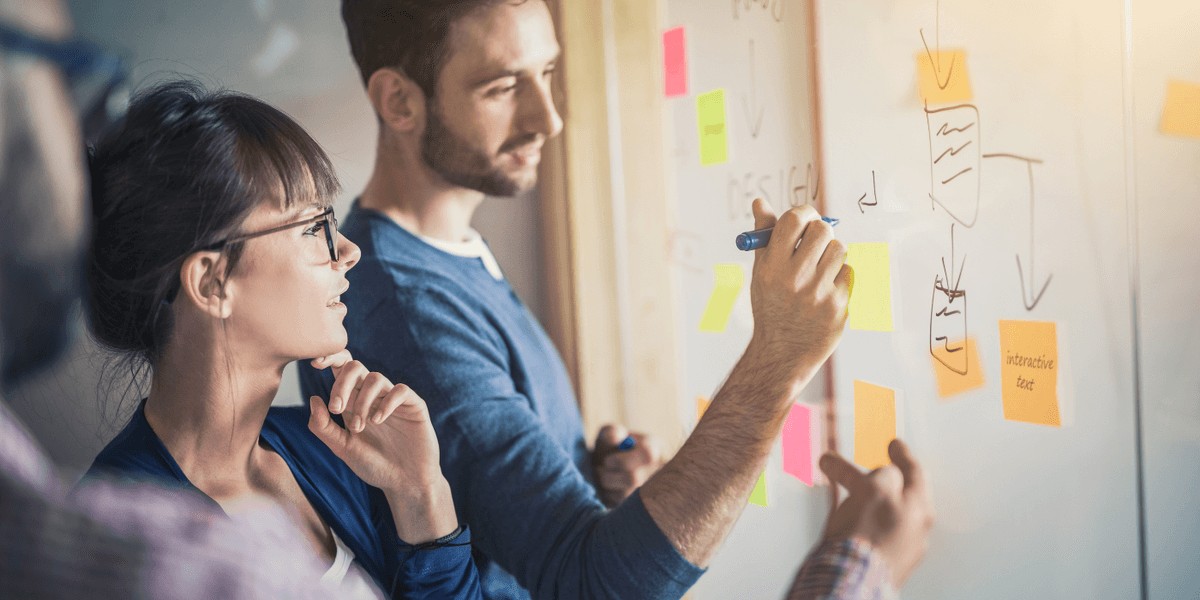 Trois personnes collaborent devant un tableau blanc couvert de notes autocollantes et de diagrammes, une personne écrit tandis que les autres observent et discutent d’idées. Trois personnes collaborent devant un tableau blanc couvert de notes autocollantes et de diagrammes, une personne écrit tandis que les autres observent et discutent d’idées.