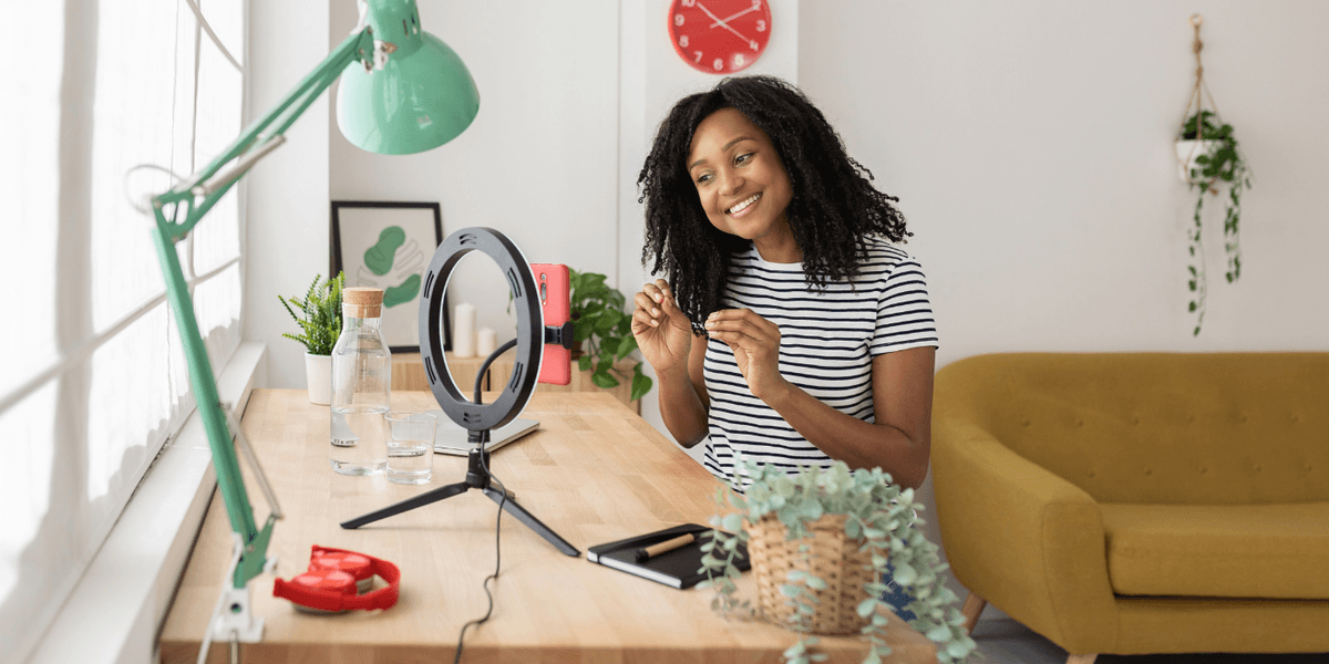 Une femme assise devant un bureau, en train de tourner une vidéo à l’aide de son téléphone intelligent. Une femme assise devant un bureau, en train de tourner une vidéo à l’aide de son téléphone intelligent.