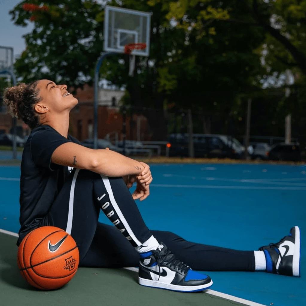 Selena smiles sitting on the basketball court wearing Jordans Selena smiles sitting on the basketball court wearing Jordans