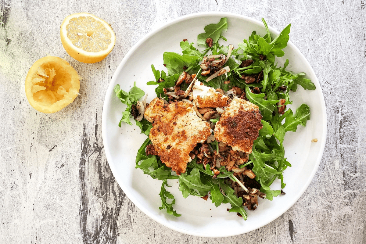 fried cod on top of a beg of arugula and a sliced lemon fried cod on top of a beg of arugula and a sliced lemon