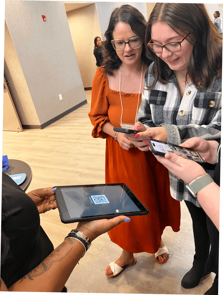 Event guests scanning a QR code held by an attendant to receive their digital photos. Event guests scanning a QR code held by an attendant to receive their digital photos.