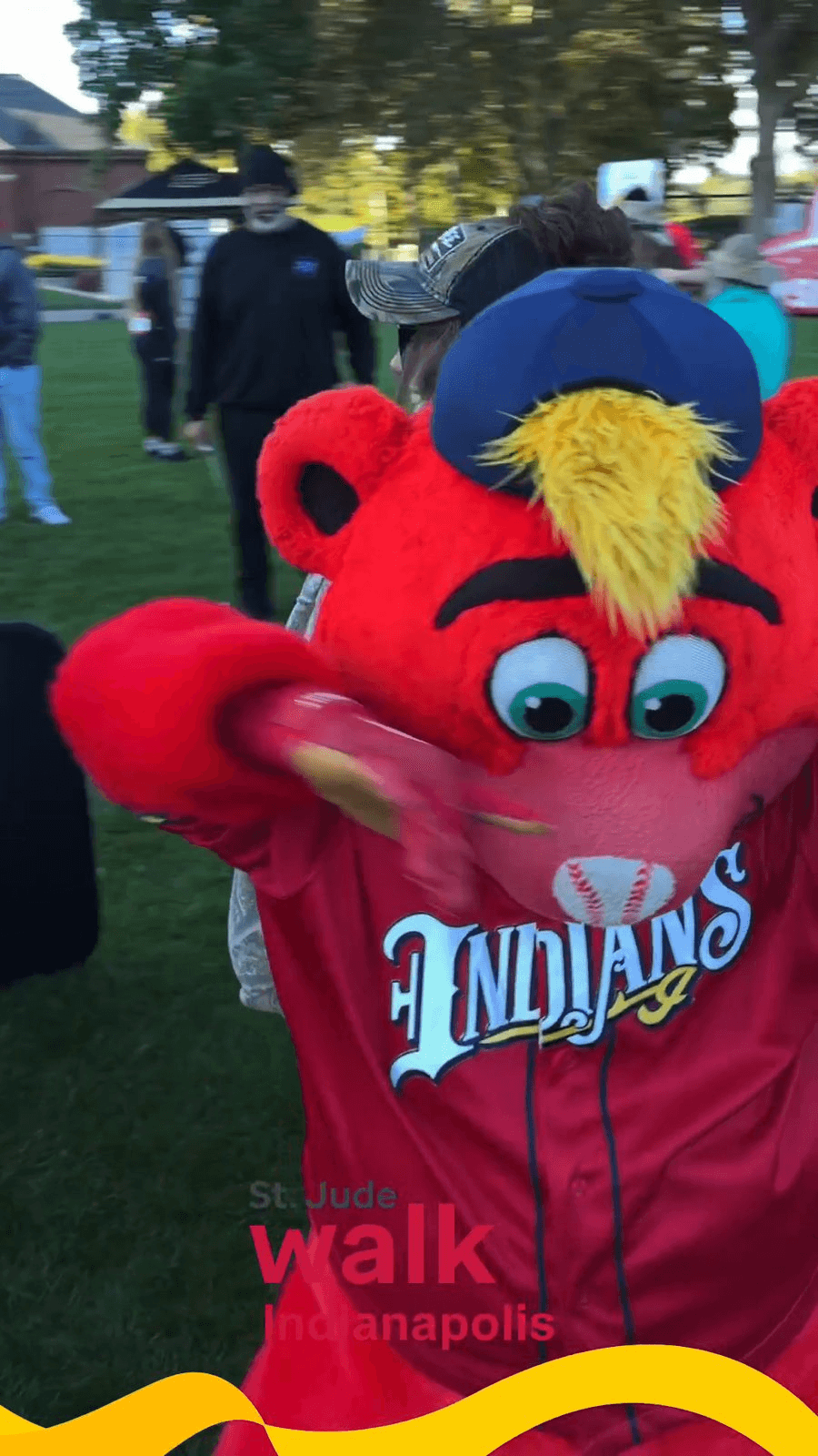 A red mascot in a baseball jersey dances in front of the 360 photo booth at a charity walk A red mascot in a baseball jersey dances in front of the 360 photo booth at a charity walk