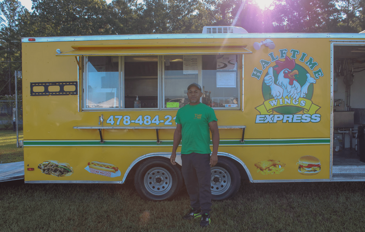 Woman in denim shirt getting food from a food truck vendor Woman in denim shirt getting food from a food truck vendor