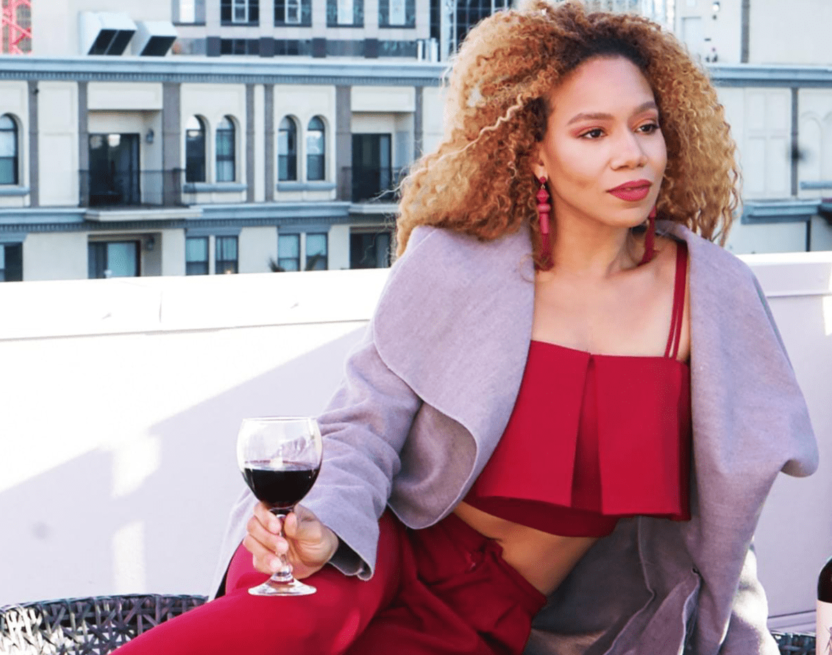 Model laid across table holding wine glass Model laid across table holding wine glass
