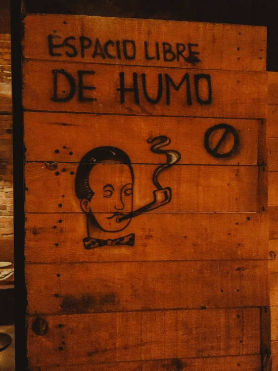 street art sign that reads espacio libre de humo above a circle with a line and a hipster man with bowtie and mustache smoking a cigar street art sign that reads espacio libre de humo above a circle with a line and a hipster man with bowtie and mustache smoking a cigar
