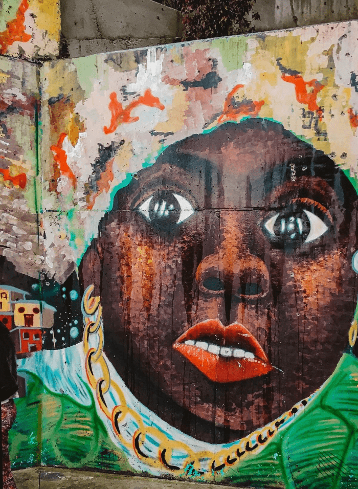 Street art of black woman with red lips and white teeth, gold chain and head wrap in comuna 13 Commune 13 San Javier Street art of black woman with red lips and white teeth, gold chain and head wrap in comuna 13 Commune 13 San Javier
