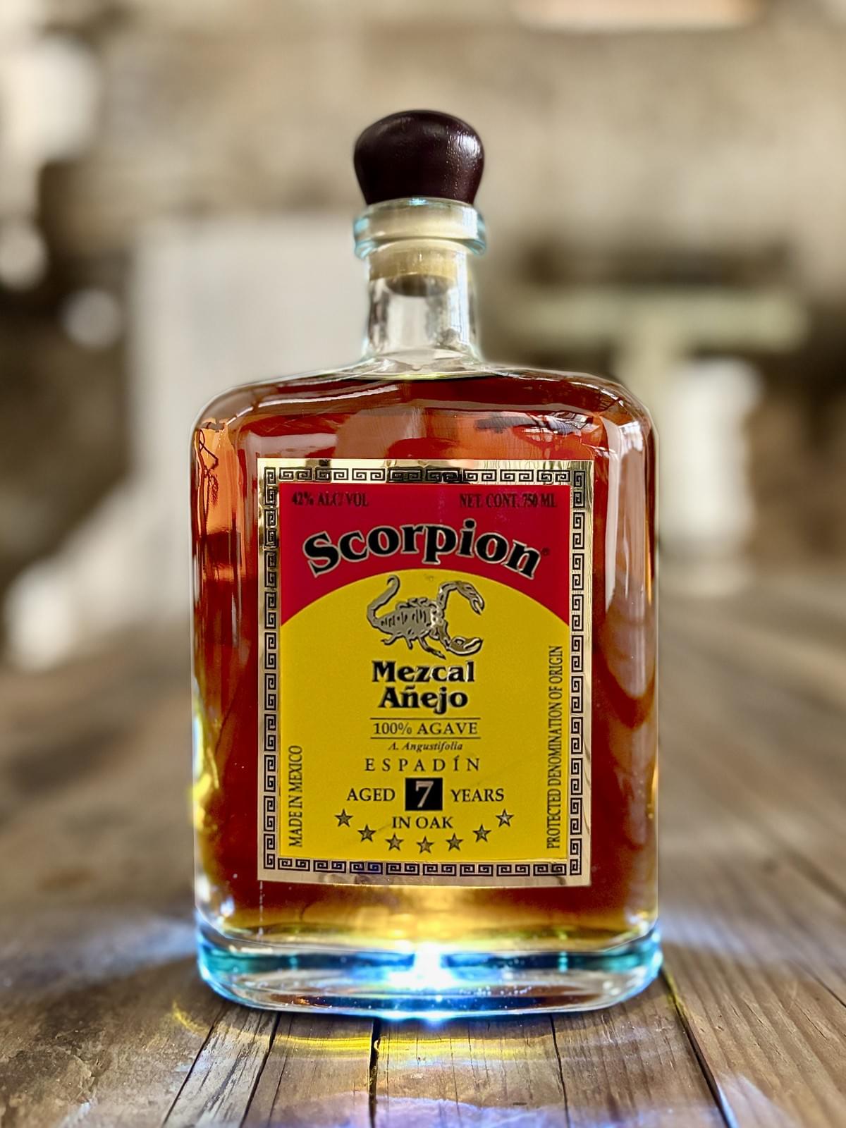 0mL bottle of Scorpion Mezcal Espadín 7 Year Extra Añejo on a rustic wooden table. 0mL bottle of Scorpion Mezcal Espadín 7 Year Extra Añejo on a rustic wooden table.