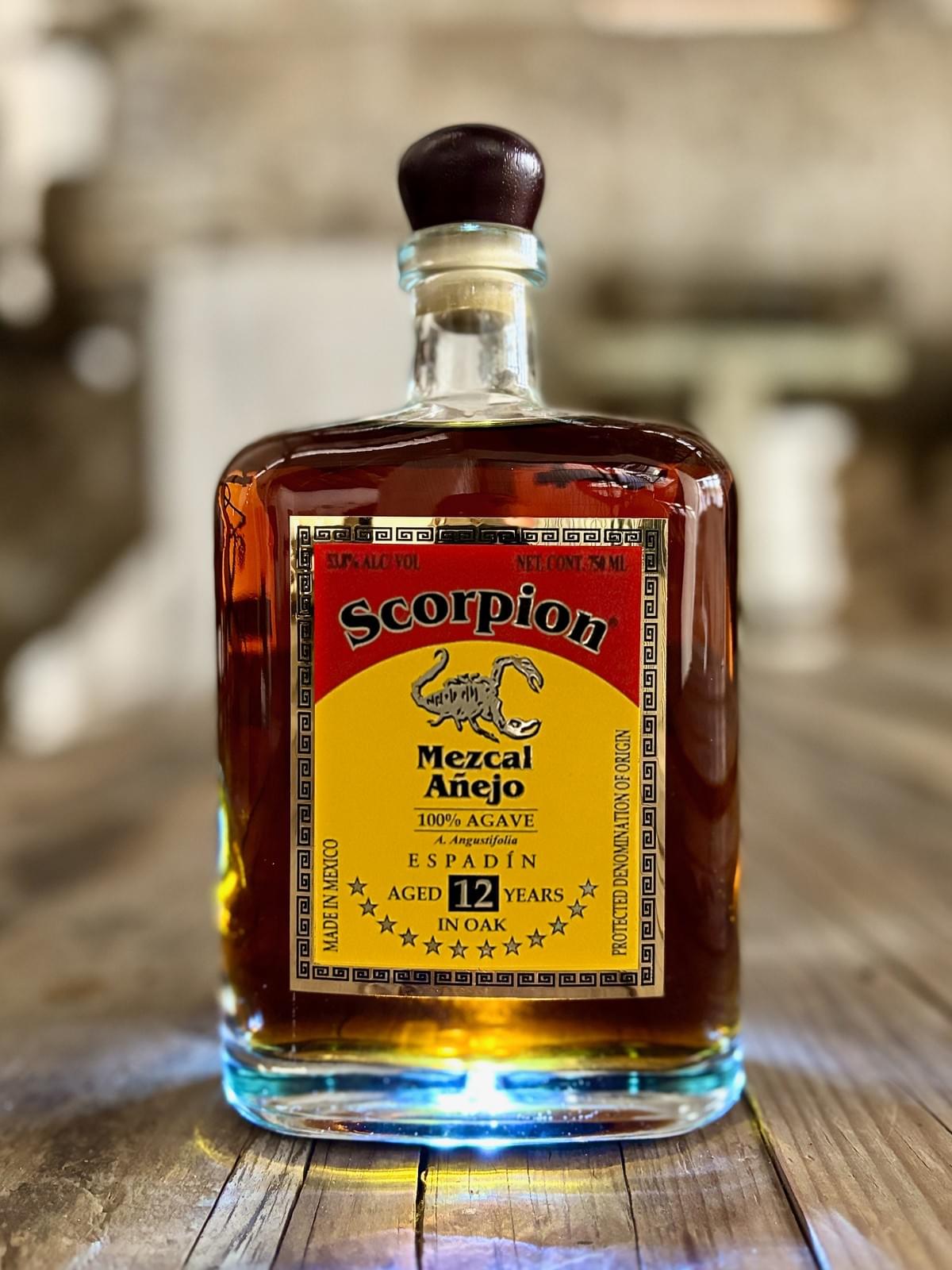 0mL bottle of Scorpion Mezcal Espadín 12 Year Extra Añejo on a rustic wooden table. 0mL bottle of Scorpion Mezcal Espadín 12 Year Extra Añejo on a rustic wooden table.