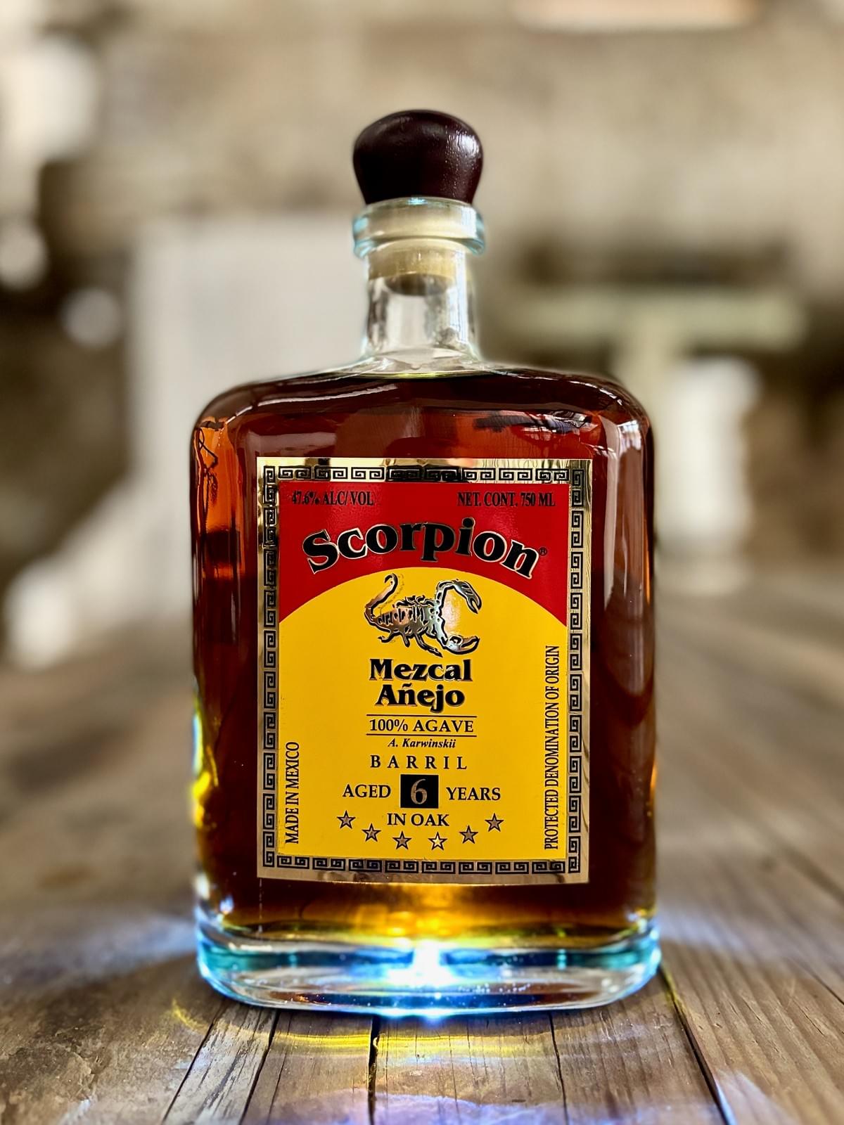 0mL bottle of Scorpion Mezcal Barril 6 Year Extra Añejo on a rustic wooden table. 0mL bottle of Scorpion Mezcal Barril 6 Year Extra Añejo on a rustic wooden table.