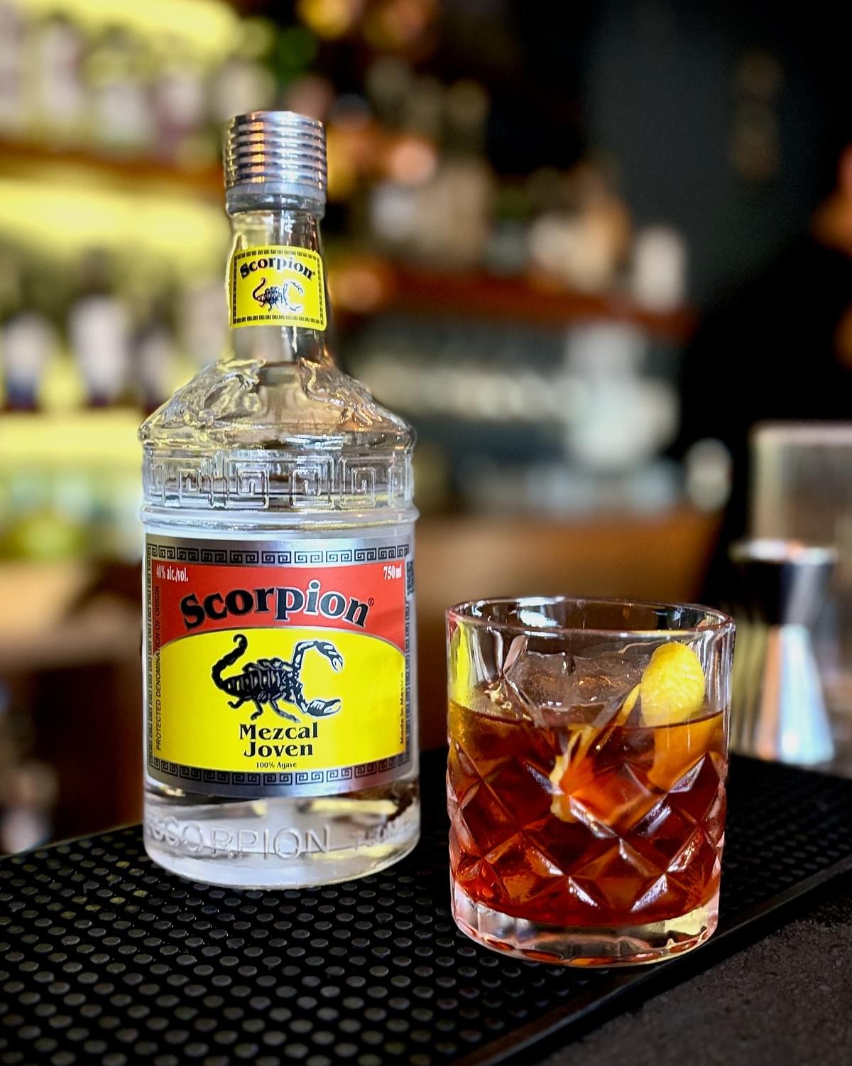 750mL bottle of Scorpion Mezcal Joven and a Mezcal Negroni cocktail in a short cocktail glass. 750mL bottle of Scorpion Mezcal Joven and a Mezcal Negroni cocktail in a short cocktail glass.