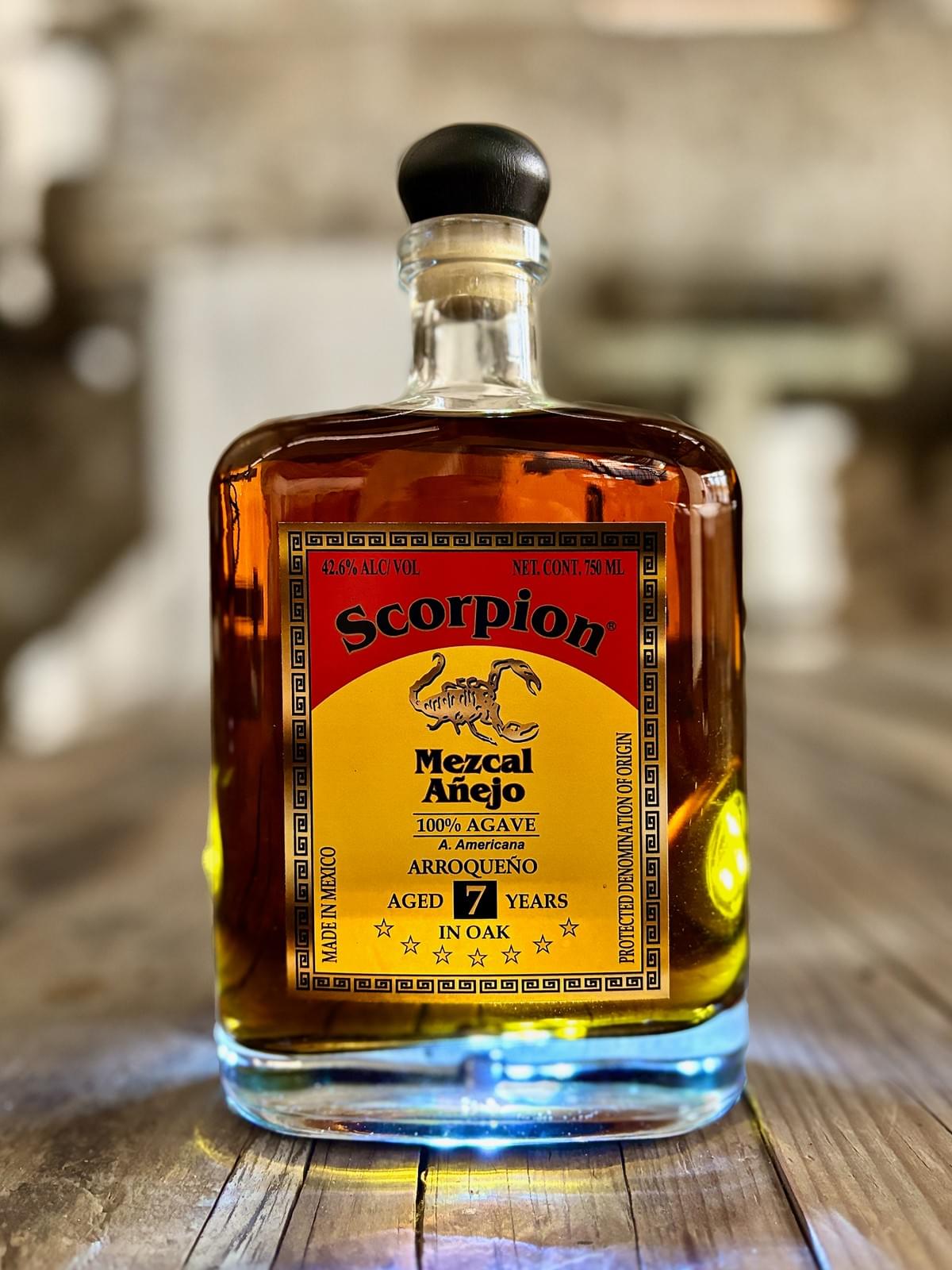 0mL bottle of Scorpion Mezcal Arroqueño 7 Year Extra Añejo on a rustic wooden table. 0mL bottle of Scorpion Mezcal Arroqueño 7 Year Extra Añejo on a rustic wooden table.