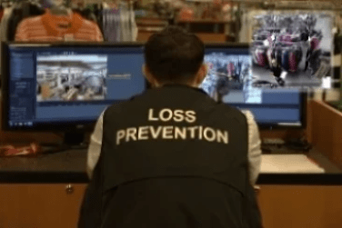 Rear view of Loss Prevention officer sitting at monitor in retail shop observing Rear view of Loss Prevention officer sitting at monitor in retail shop observing