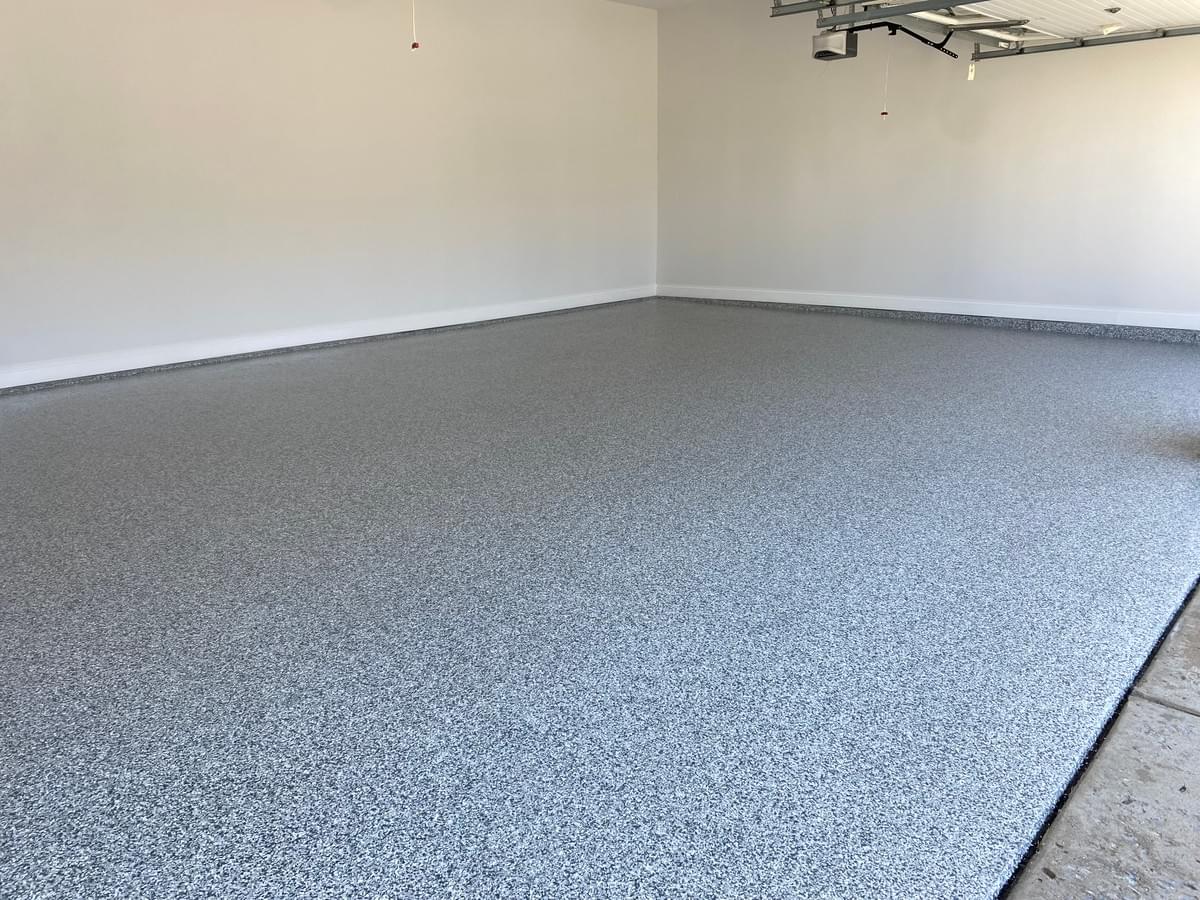 Quality Floor Coatings, a garage floor solutions company in Ellisville, MO, showcasing a garage floor makeover. The image shows a gray and black patterned epoxy floor installed by Quality Floor Coatings. The floor is glossy, smooth, and durable, providing a modern and functional look to the garage. Quality Floor Coatings, a garage floor solutions company in Ellisville, MO, showcasing a garage floor makeover. The image shows a gray and black patterned epoxy floor installed by Quality Floor Coatings. The floor is glossy, smooth, and durable, providing a modern and functional look to the garage.