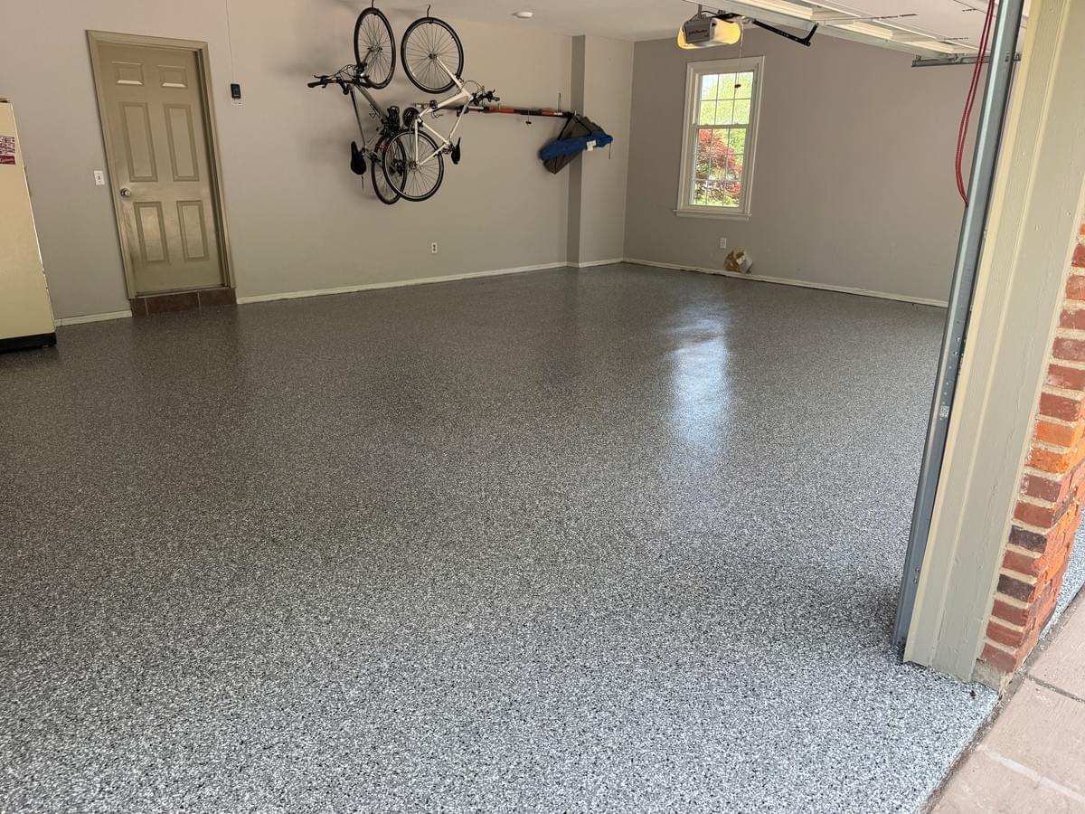 Quality Floor Coatings, a garage floor solutions company in Ellisville, MO, showcasing a garage floor makeover. The image shows a gray and black patterned epoxy floor installed by Quality Floor Coatings. The floor is glossy, smooth, and durable, providing a modern and functional look to the garage. Quality Floor Coatings, a garage floor solutions company in Ellisville, MO, showcasing a garage floor makeover. The image shows a gray and black patterned epoxy floor installed by Quality Floor Coatings. The floor is glossy, smooth, and durable, providing a modern and functional look to the garage.