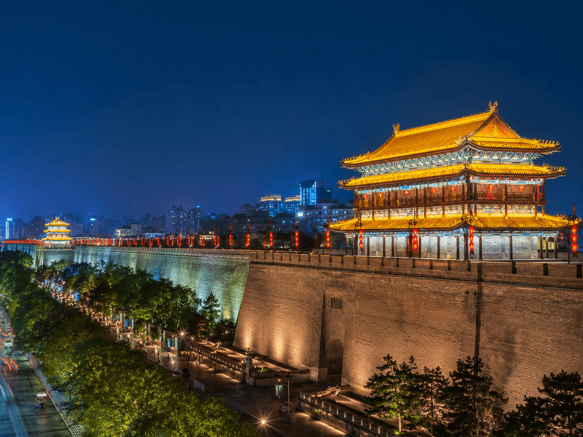 Xi’an City Wall and traditional gate tower illuminated against a deep blue evening sky. Xi’an City Wall and traditional gate tower illuminated against a deep blue evening sky.