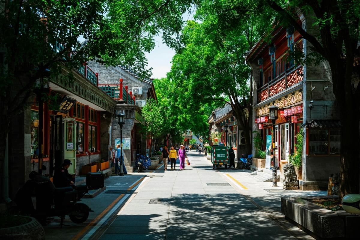 A traditional Beijing hutong alley with bicycles, a scooter, and vibrant red lanterns hanging overhead A traditional Beijing hutong alley with bicycles, a scooter, and vibrant red lanterns hanging overhead