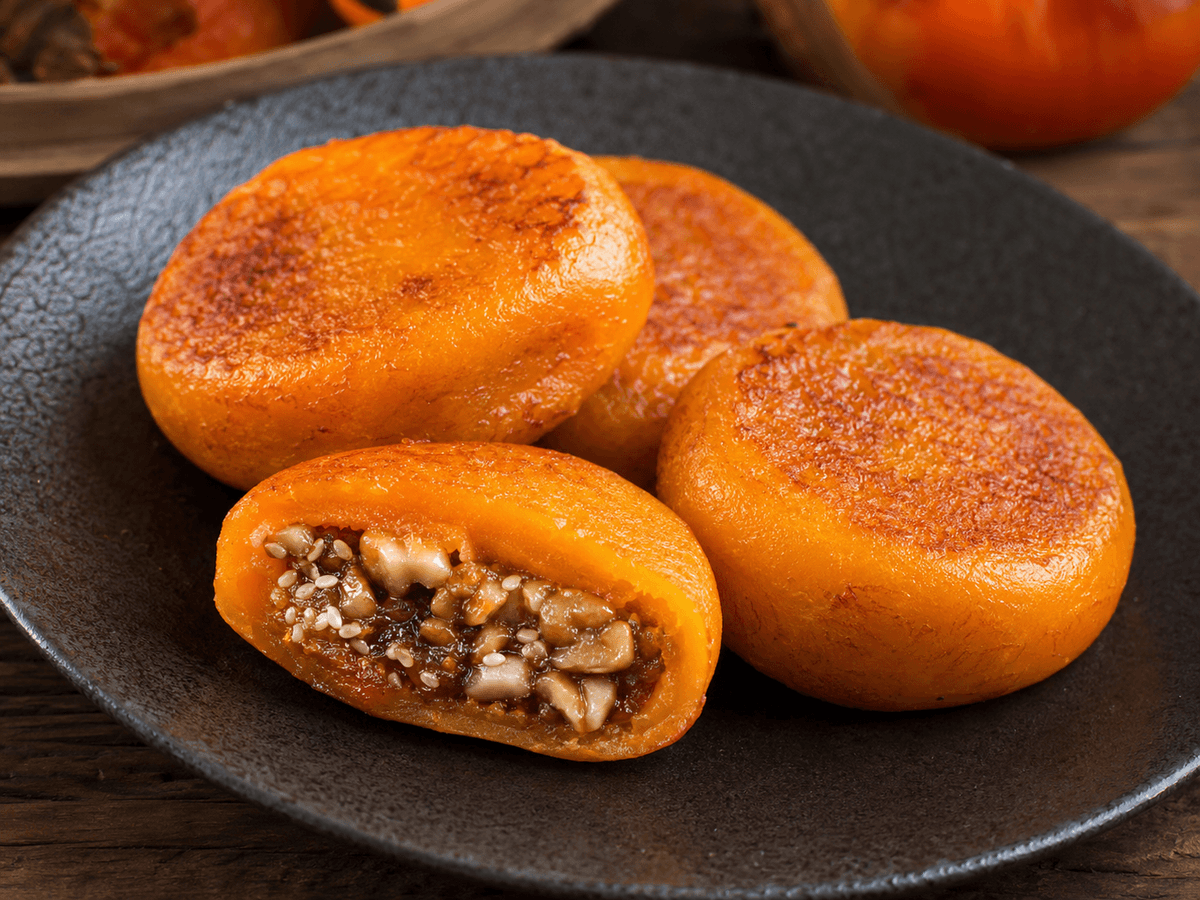Golden Xi’an persimmon cakes with a sweet walnut and sesame filling on a ceramic plate. Golden Xi’an persimmon cakes with a sweet walnut and sesame filling on a ceramic plate.
