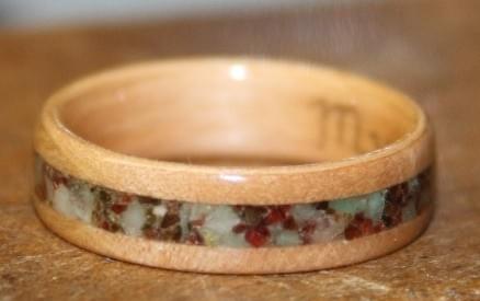 This is an Arbutus (Madrone) wood ring with an inlay of rough emerald and garnet This is an Arbutus (Madrone) wood ring with an inlay of rough emerald and garnet