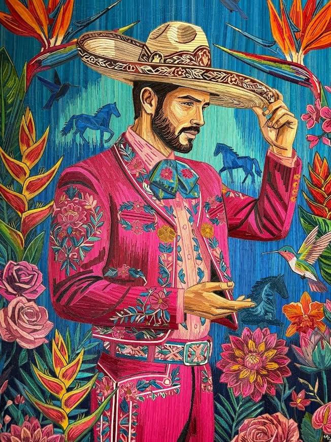 Contemporary popotillo artwork by Ariosto Rivera featuring a Mexican charro in a vibrant pink suit surrounded by flowers, horses, birds of paradise, and a hummingbird. Contemporary popotillo artwork by Ariosto Rivera featuring a Mexican charro in a vibrant pink suit surrounded by flowers, horses, birds of paradise, and a hummingbird.