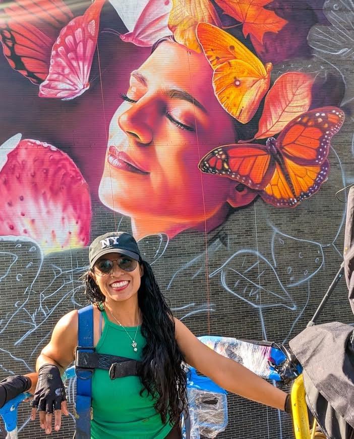Mexican artist Adry del Rocío standing in front of a large butterfly mural featuring a woman's portrait and vibrant monarch butterflies. Mexican artist Adry del Rocío standing in front of a large butterfly mural featuring a woman's portrait and vibrant monarch butterflies.