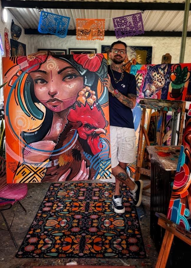 Colombian artist Daniel Acosta León standing in his studio beside a colorful painting featuring a woman and rooster, surrounded by vibrant original artworks and creative materials. Colombian artist Daniel Acosta León standing in his studio beside a colorful painting featuring a woman and rooster, surrounded by vibrant original artworks and creative materials.