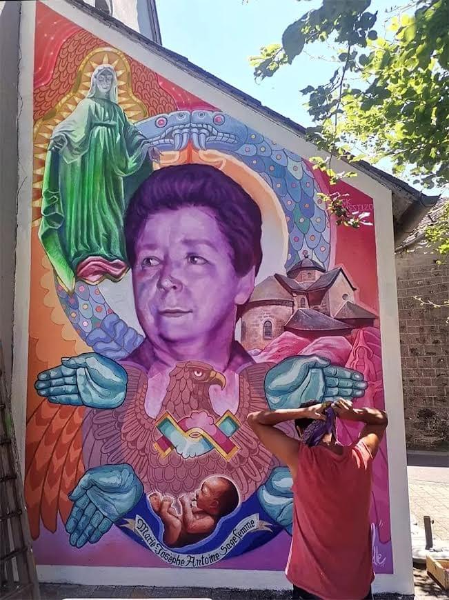 Mural by Mexican artist Nick Mestizo featuring a community figure surrounded by spiritual symbols, protective hands, an eagle, and cultural imagery, reflecting identity, resilience, and collective memory. Mural by Mexican artist Nick Mestizo featuring a community figure surrounded by spiritual symbols, protective hands, an eagle, and cultural imagery, reflecting identity, resilience, and collective memory.