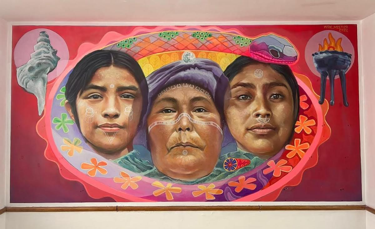 Mural by Mexican artist Nick Mestizo featuring three Indigenous women surrounded by sacred symbols, flowers, and natural elements, celebrating cultural identity, ancestry, and resilience. Mural by Mexican artist Nick Mestizo featuring three Indigenous women surrounded by sacred symbols, flowers, and natural elements, celebrating cultural identity, ancestry, and resilience.
