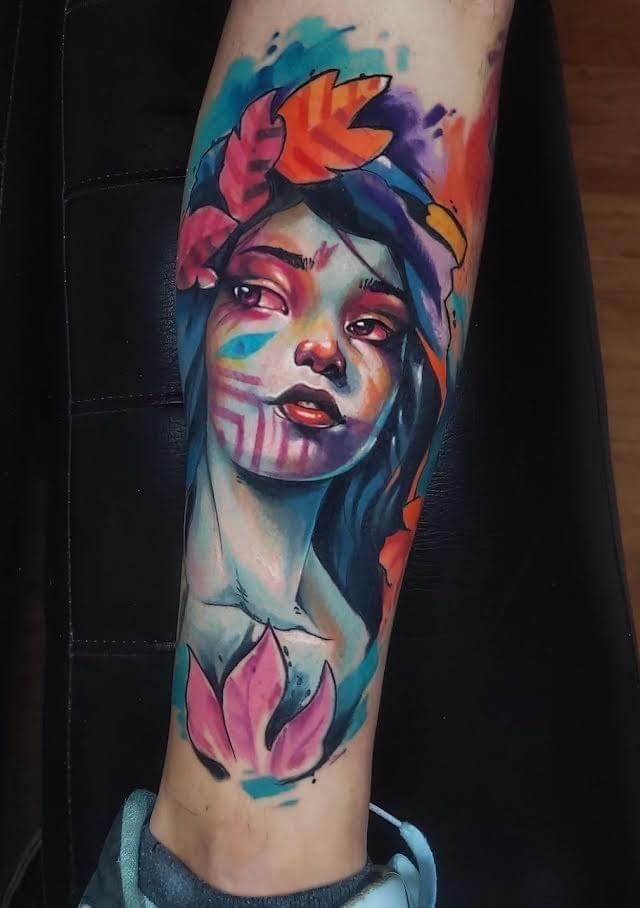 Colorful portrait tattoo by Daniel Acosta León featuring a young woman with floral elements, expressive facial markings, and vibrant watercolor inspired colors blending pink, blue, orange, and purple tones. Colorful portrait tattoo by Daniel Acosta León featuring a young woman with floral elements, expressive facial markings, and vibrant watercolor inspired colors blending pink, blue, orange, and purple tones.