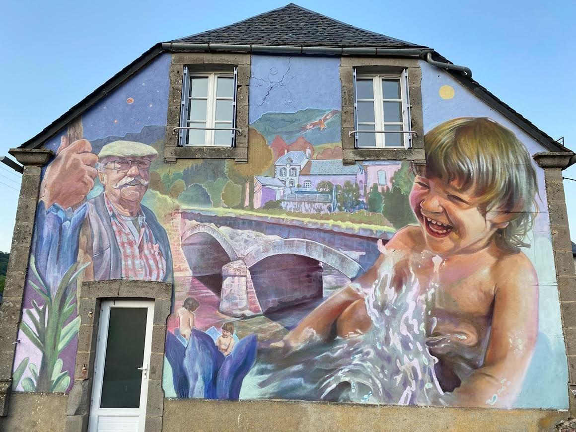 Community mural by Mexican artist Nick Mestizo featuring local residents, a child playing in water, and a village landscape, celebrating memory, identity, and connection to place. Community mural by Mexican artist Nick Mestizo featuring local residents, a child playing in water, and a village landscape, celebrating memory, identity, and connection to place.