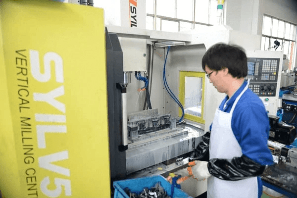 A CNC lathe operator loading a workpiece into a SYIL CNC mill A CNC lathe operator loading a workpiece into a SYIL CNC mill