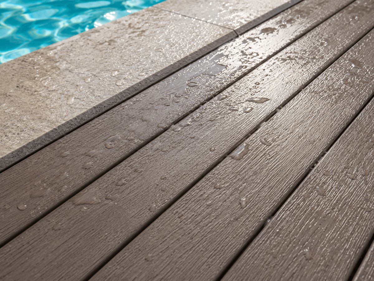 Close-up of wet composite decking near a pool edge showing texture and drainage detail Close-up of wet composite decking near a pool edge showing texture and drainage detail