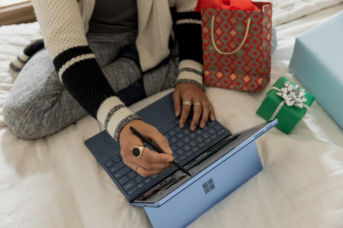 Shopper using a tablet beside wrapped purchases Shopper using a tablet beside wrapped purchases
