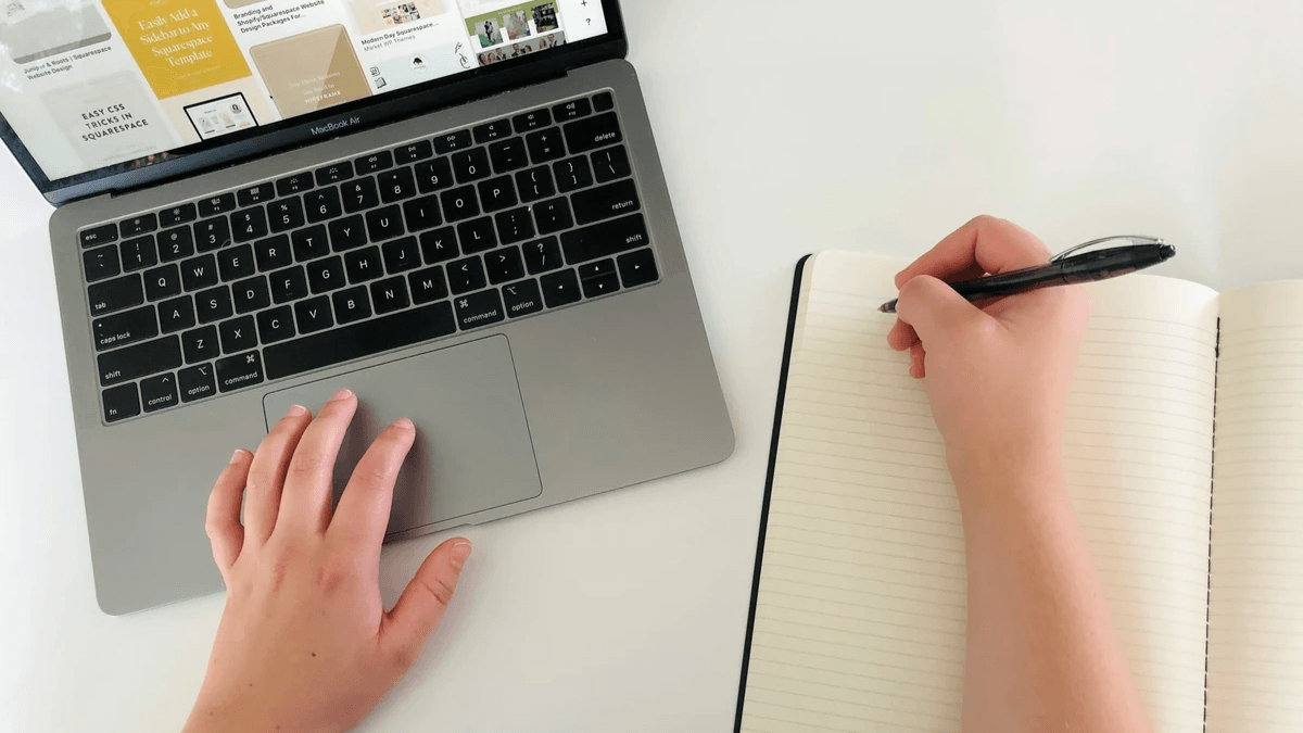 Content editor reviewing a website page beside a laptop and notebook Content editor reviewing a website page beside a laptop and notebook