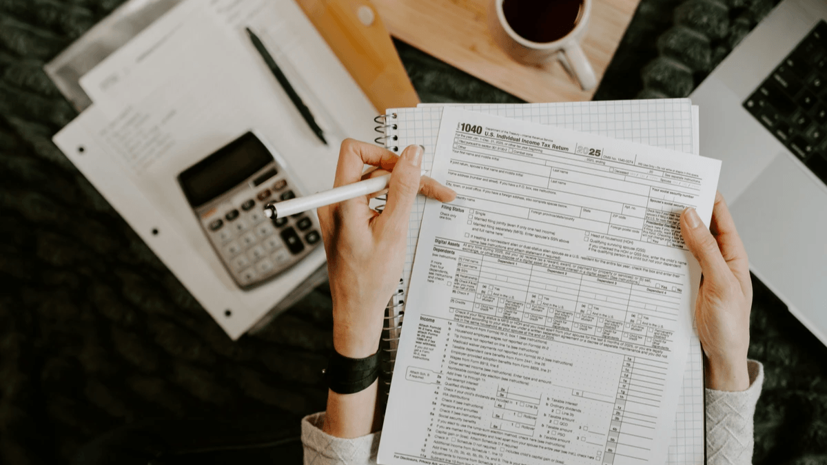 Person reviewing project documents beside a calculator and laptop Person reviewing project documents beside a calculator and laptop