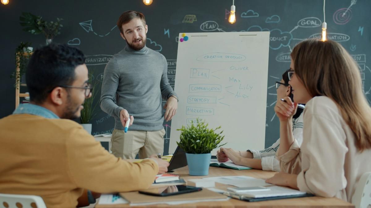 Business team planning website priorities together at a whiteboard Business team planning website priorities together at a whiteboard