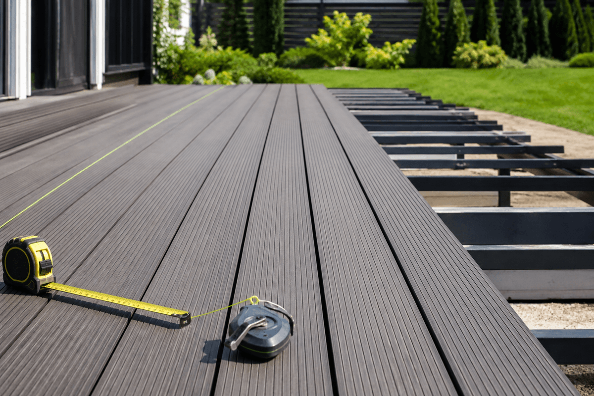 Installer checking straight gap lines on grooved composite decking Installer checking straight gap lines on grooved composite decking