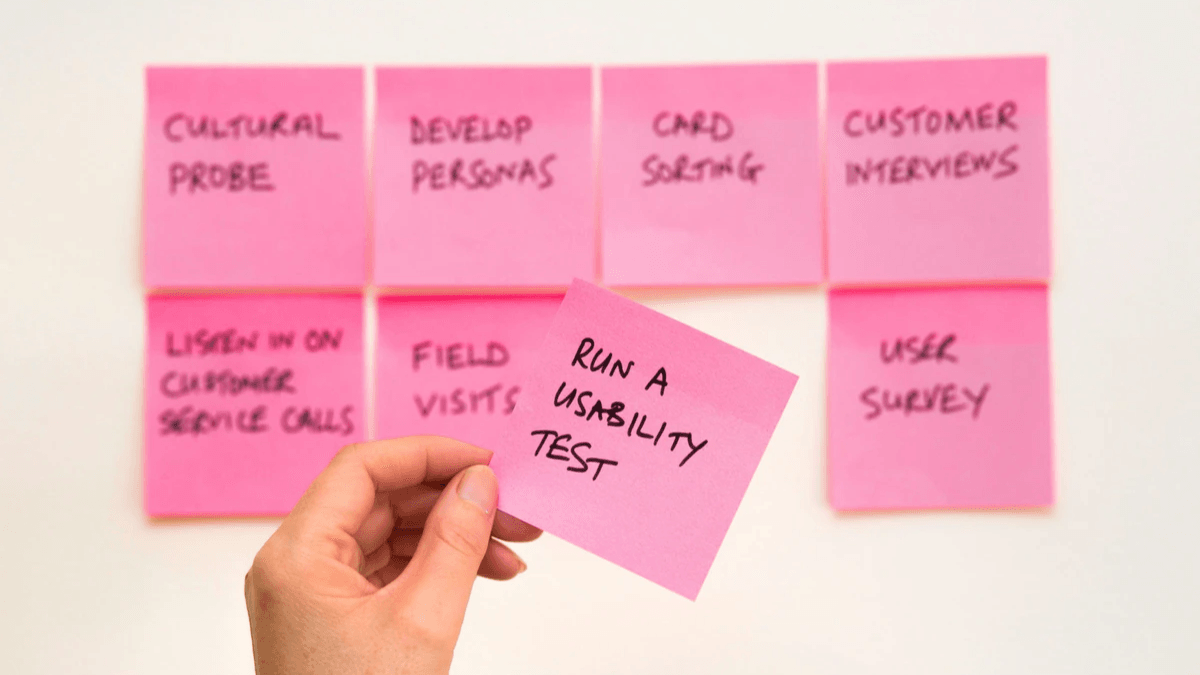 Researcher holding a sticky note that says run a usability test Researcher holding a sticky note that says run a usability test
